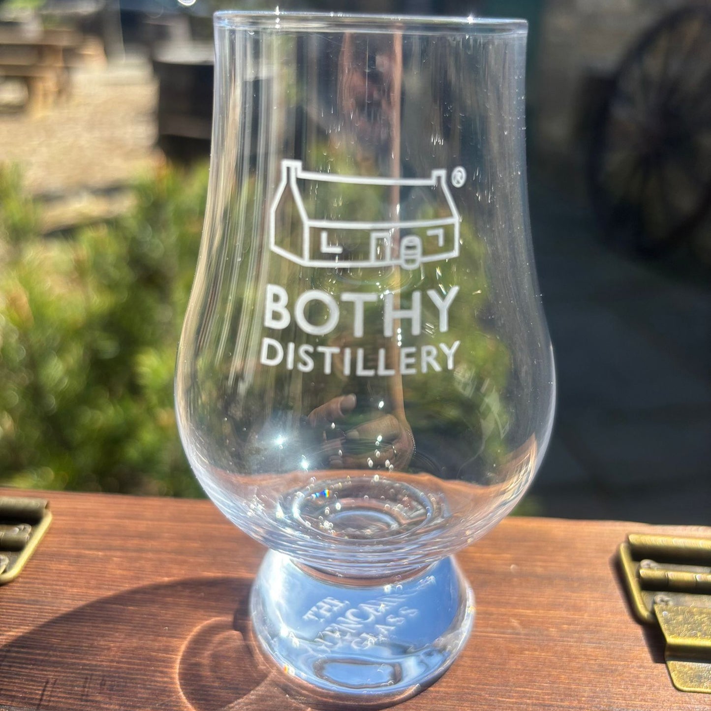 Clear Glencairn glass with engraved text on a wooden surface, blurred background