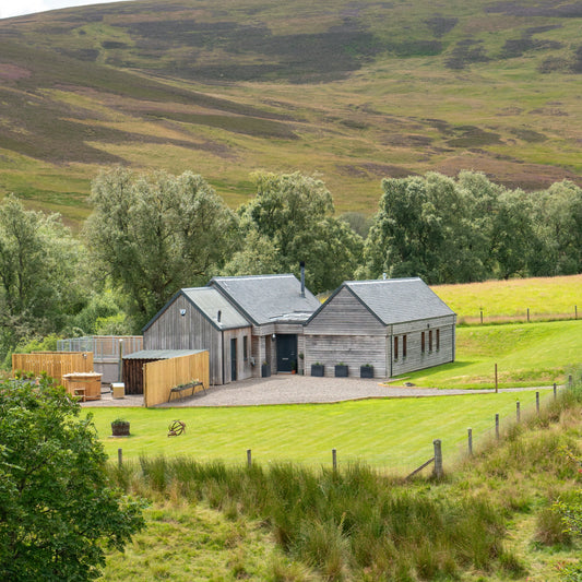 Modern house in a rural setting with green fields and hills in the background