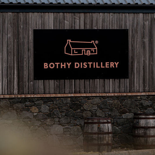 Wooden building with 'Bothy Distillery' sign in a rural setting