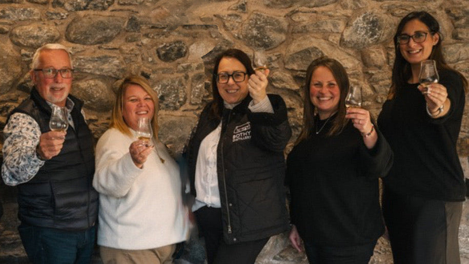 Five people holding glasses in front of a stone wall
