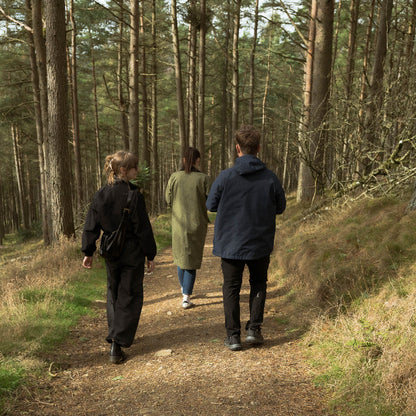 Three people walking along a path in a forest